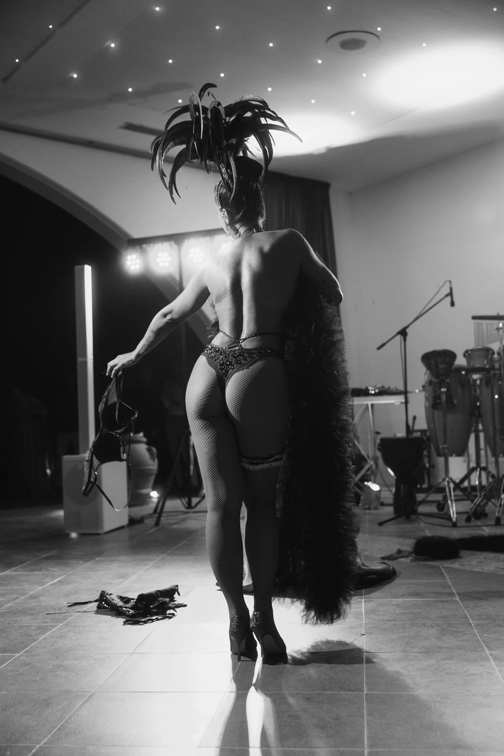 Performer Burlesque con costume di scena e piume durante una performance, fotografia in bianco e nero.